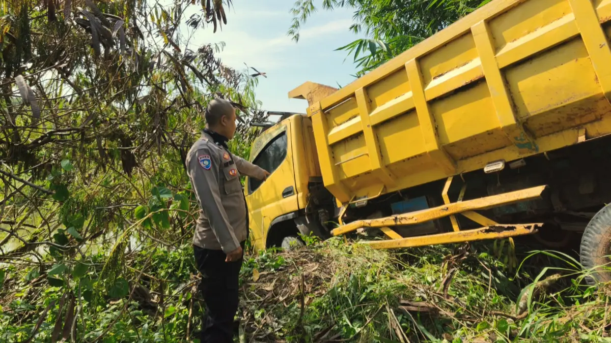 Bhabinkamtibmas Desa Tamansari, Aipda Asep Rohmat Mulyana mengecek kondisi truk yang terperosok di Rumpin Bogor.  (Nasir/ Radar Bogor)