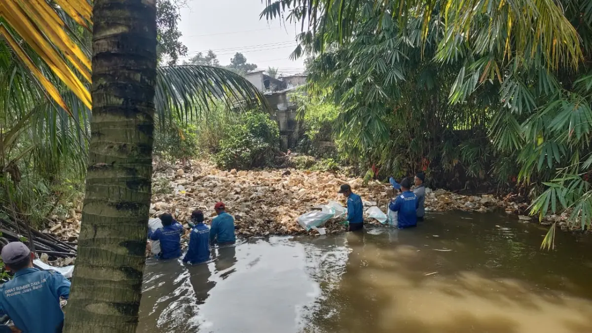 Petugas saat membersihkan tumpukan sampah di Jembatan Villa Asia, Bojonggede, Kabupaten Bogor. Foto: Kecamatan Bojonggede.