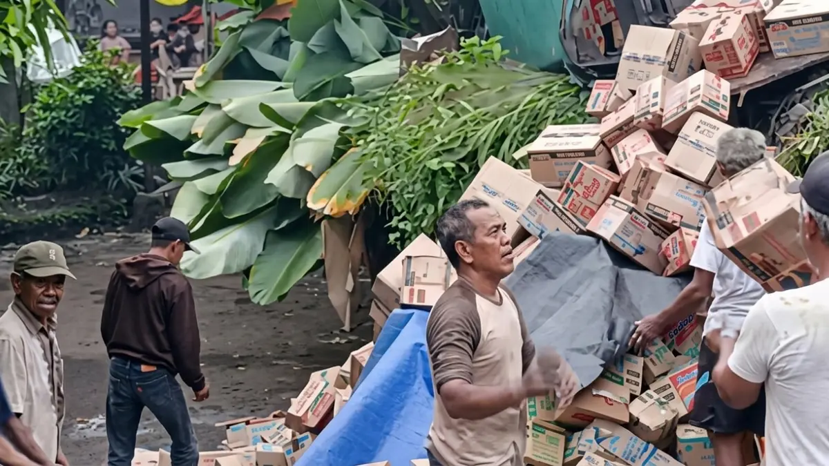 Warga membantu evakuasi muatan truk yang terguling di Jalan raya Ciampea-Leuwiliang, Sabtu 13 Juni 2026.