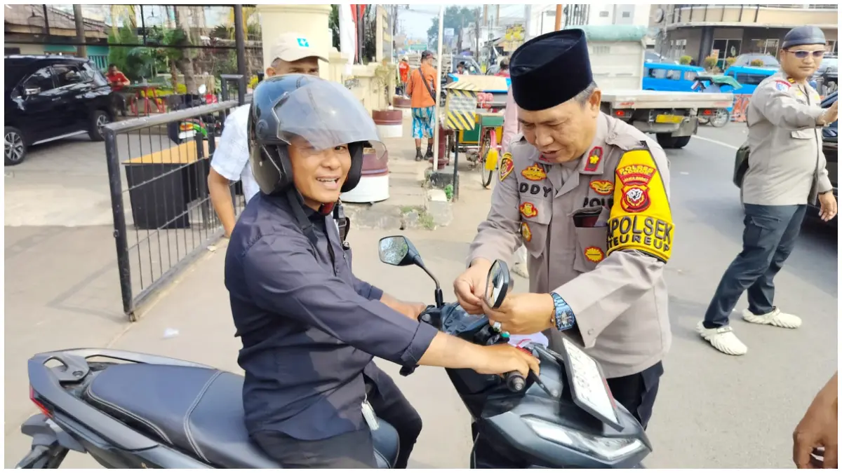 Kapolsek Citeureup, Kompol Eddy Santosa saat membagikan bendera kepada pengendara yang melewati Mapolsek Citeureup, Kecamatan Citeureup, Kabupaten Bogor. (Foto: Muhammad Ali/Radar Bogor)