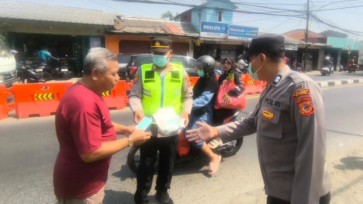 Anggota Polsek Sukaraja membagikan masker di depan Mako Polsek Sukaraja, Kabupaten Bogor, Minggu, 6 September 2026. (Dok. Polsek Sukaraja)
