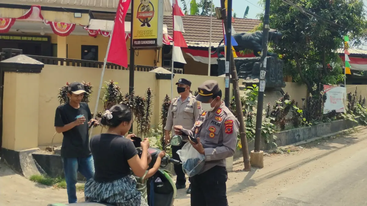 Kapolsek Gunungsindur, AKP Ucup Supriatna membagikan masker kepada warga Bogor, Minggu 6 September 2026.  (Nasir/ Radar Bogor)