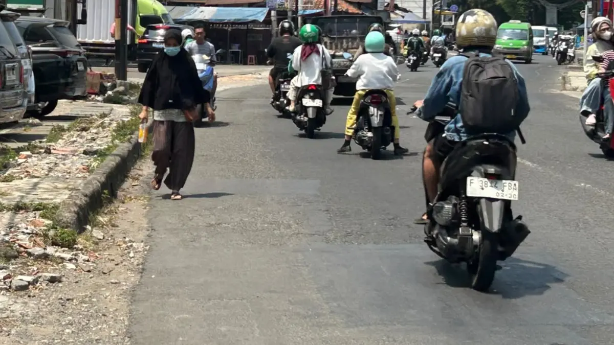Pejalan kaki yang harus berjalan ke bahu jalan karena area pedestrian di Jalan Sumeru rusak. (Raissa/Magang Radar Bogor)