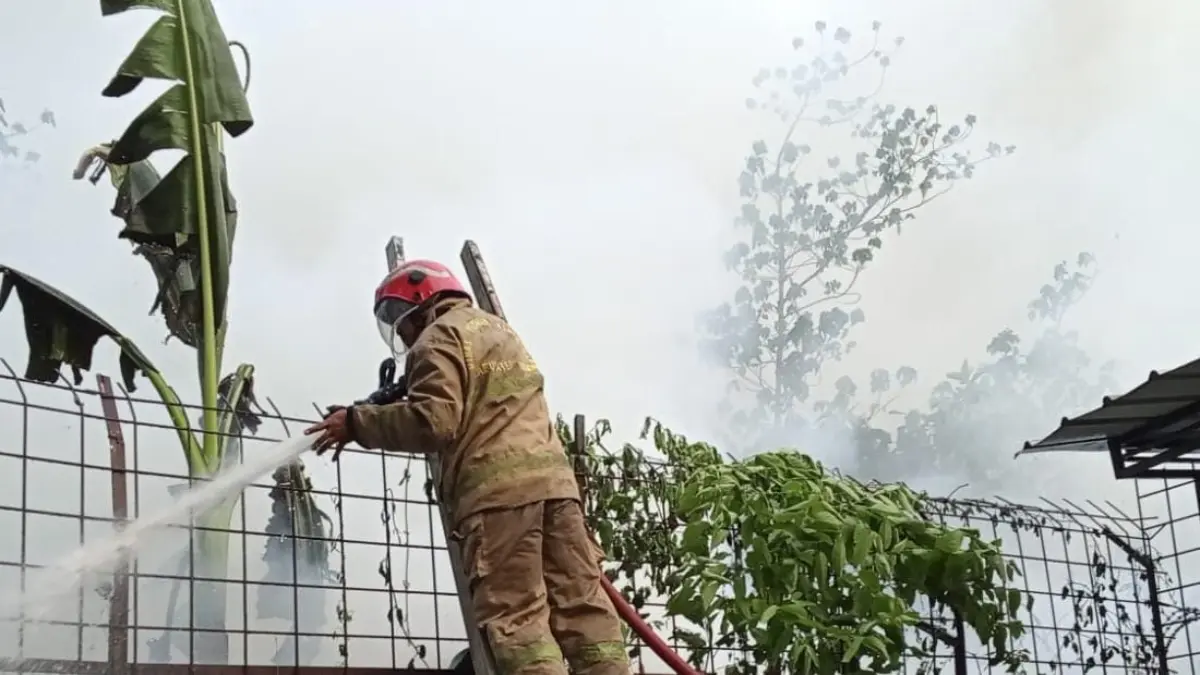 Petugas damkar saat memadamkan api dari balik tembok perumahan di Kecamatan Cileungsi, Kabupaten Bogor. (Dok. Damkar)