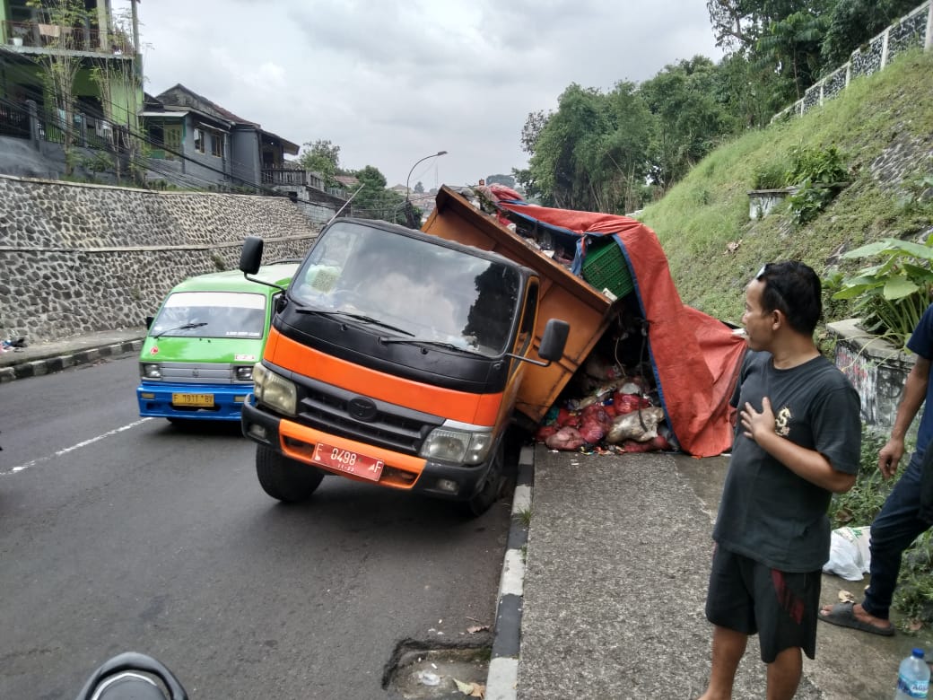 Mobil pengangkut sampah milik DLH kabupaten Bogor ambles di tanjakan sarijan akibat ban mobil masuk lubang saluran. foto sofyan/ Radar Bogor