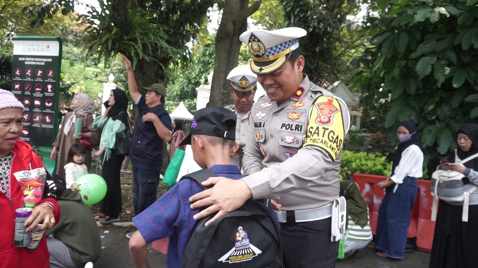 Kasat Lantas Polresta Bogor Kota membagikan tas sekolah yang dinamainya Tas Hari Raya (THR) kepada para pengunjung Kebun Raya Bogor, yang masih berusia sekolah, Sabtu (13/4/2024). Foto: Reka/Radar Bogor