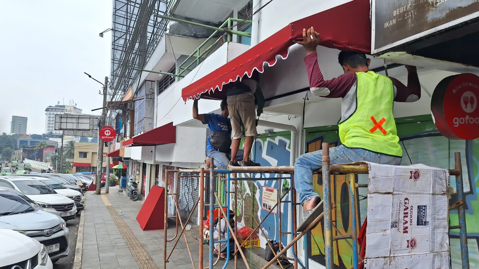 Pekerja sedang memasang tenda/ awning di pertokoan kawasan Jalan Otista Kota Bogor, Rabu (17/4/2024). FOTO : SOFYANSYAH/RADAR BOGOR