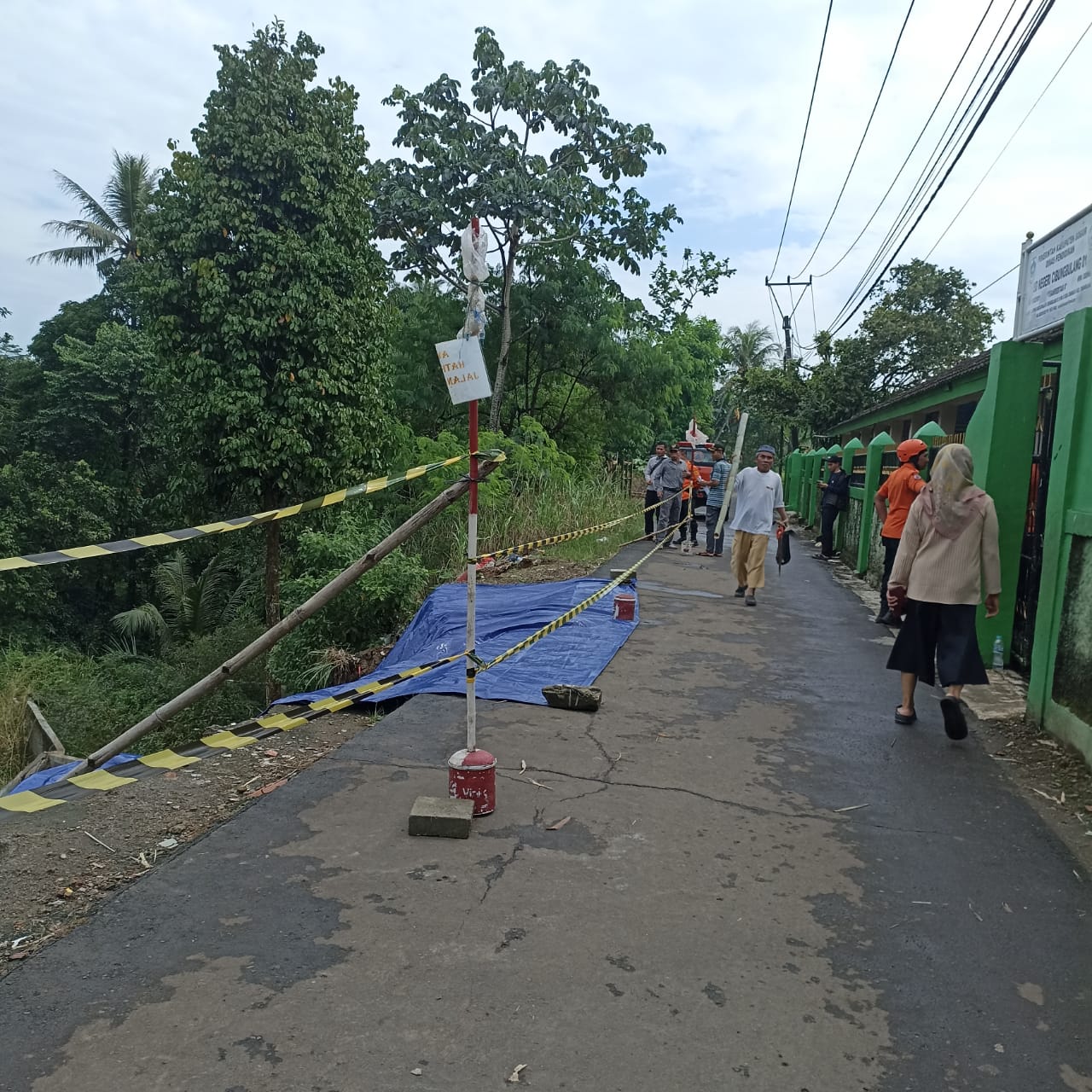 Kondisi terkini tebing yang longsor di Kampung Cibungbulang. Lokasi longsoran sudah ditutup menggunakan terpal serta garis pembatas yang dipasang Polisi dan BPBD, Senin (15/4/2024). Foto: kiriman Polsek