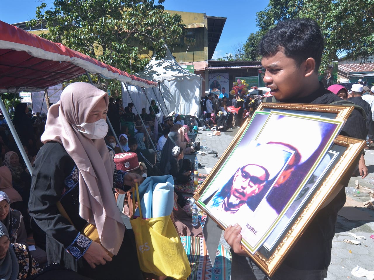 Seorang pedagang menjajakan poster bergambar Almarhum Al-Habib Idrus Bin Salim Al-Jufri atau Guru Tua kepada masyarakat yang hadir saat puncak peringatan Haul Guru Tua ke-56 di Palu.
