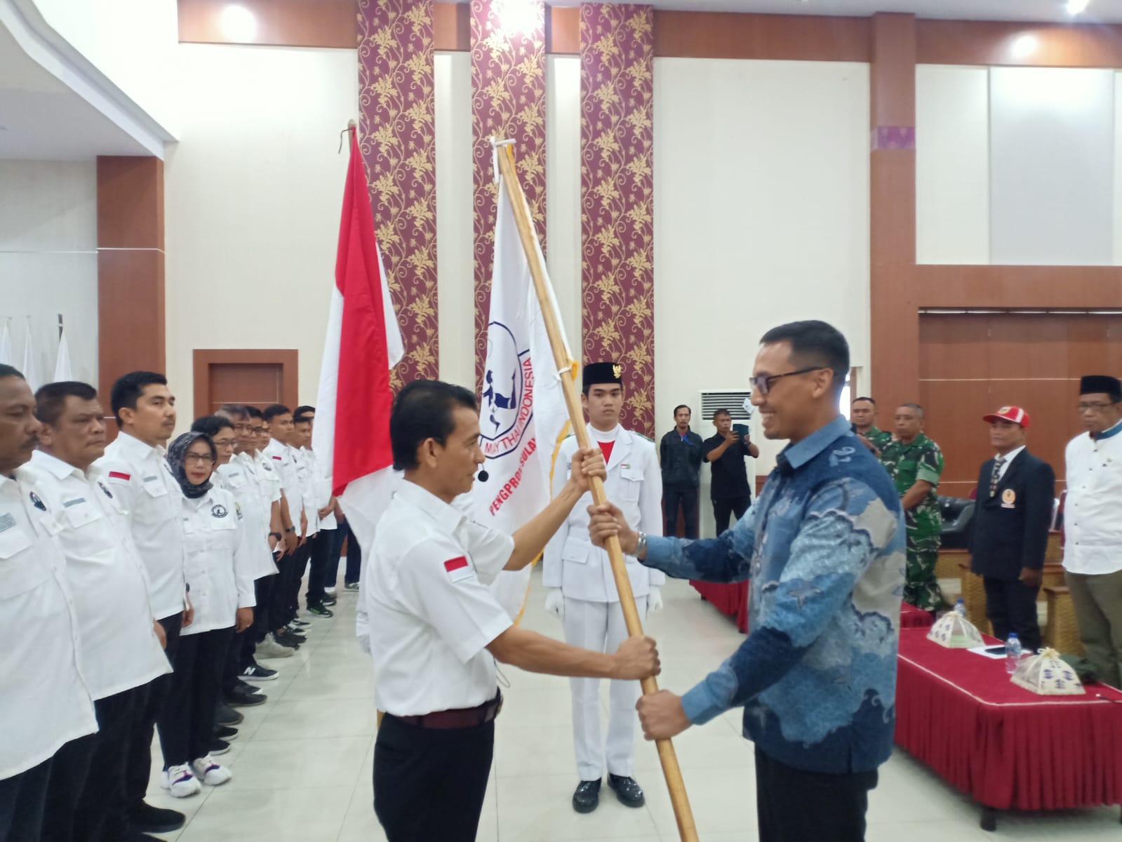 SERAHKAN PATAKA : Sekjen PP Muaythai, Azwan Karim, menyerahkan pataka Muaythai kepada ketua Muaythai Sulteng, Suandi, Jumat (11/07/2025).(FOTO : MUCHSIN SIRADJUDIN/RADAR PALU).
