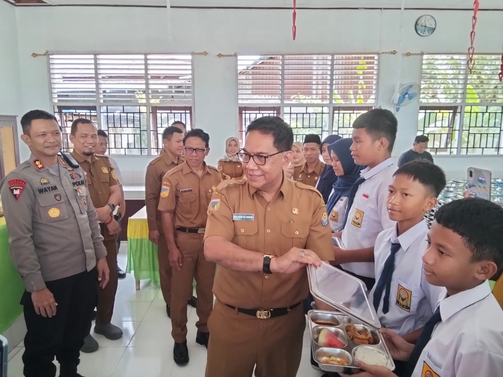 MEMBERIKAN : Tampak Kadis Kesehatan Tolitoli saat memberikan MBG kepada salah seorang siswa SMP Negeri 1.(FOTO :&nbsp;YUSLIH ANWAR/RADAR PALU).