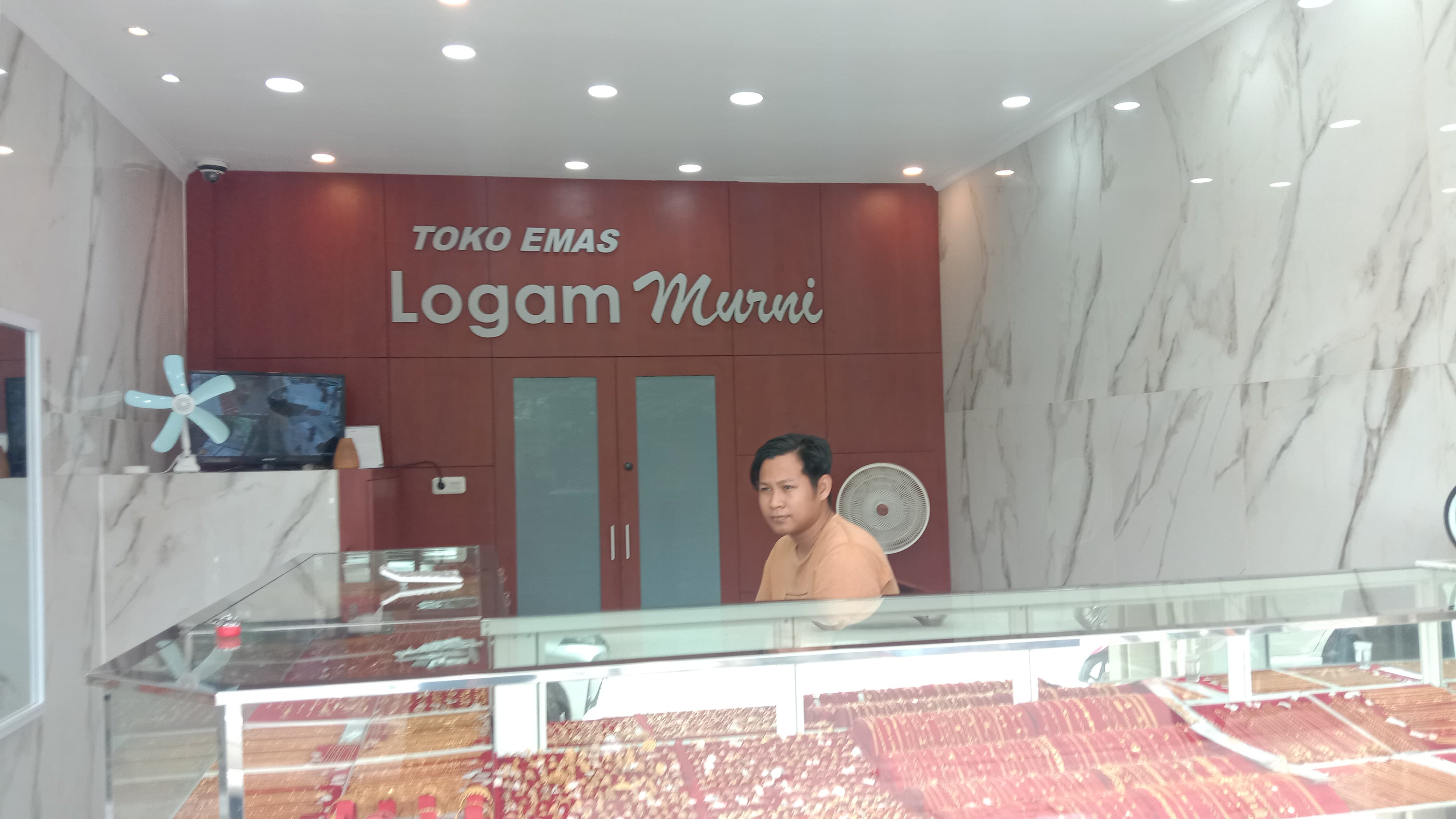 TETAP STABIL: Salah satu pedagang emas di Pasar Masomba, Agub terlihat sedang berjaga di toko pada Senin (11/8/2025).