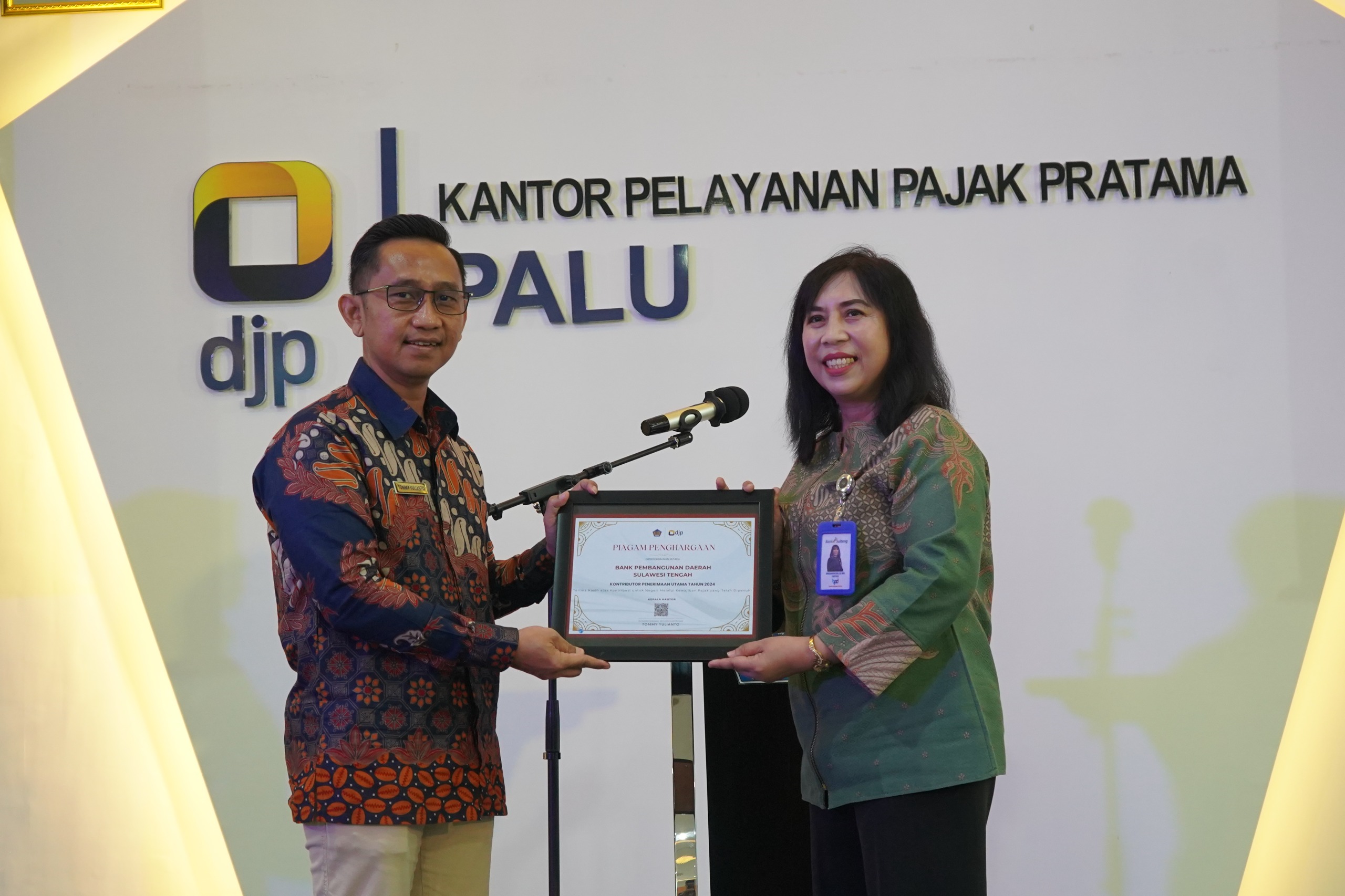 Kepala Divisi Pemasaran Bank Sulteng, Wirdaningsih saat menerima penghargaan dari Kepala KPP Pratama Palu, Tommy Yulianto.