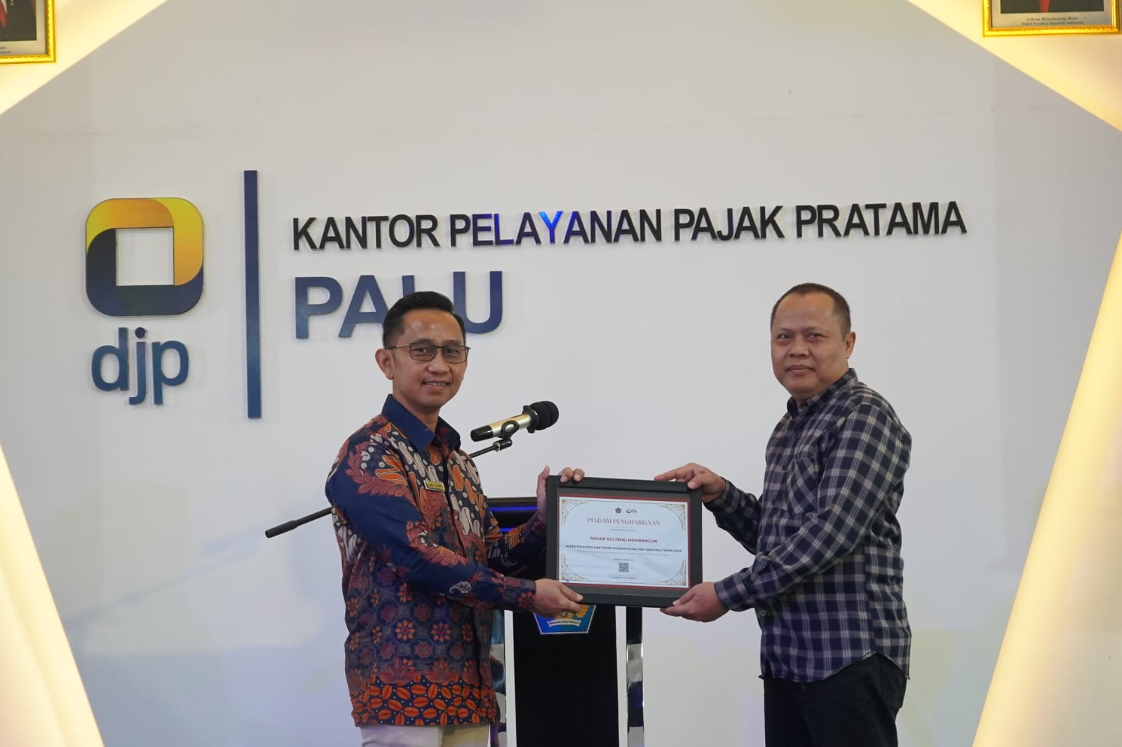 TERIMA PENGHARGAAN: Direktur Radar Palu, Murtalib saat menerima plakat penghargaan yang diserahkan langsung Kepala KPP Pratama Palu, Tommy Yulianto, Rabu (10/9).