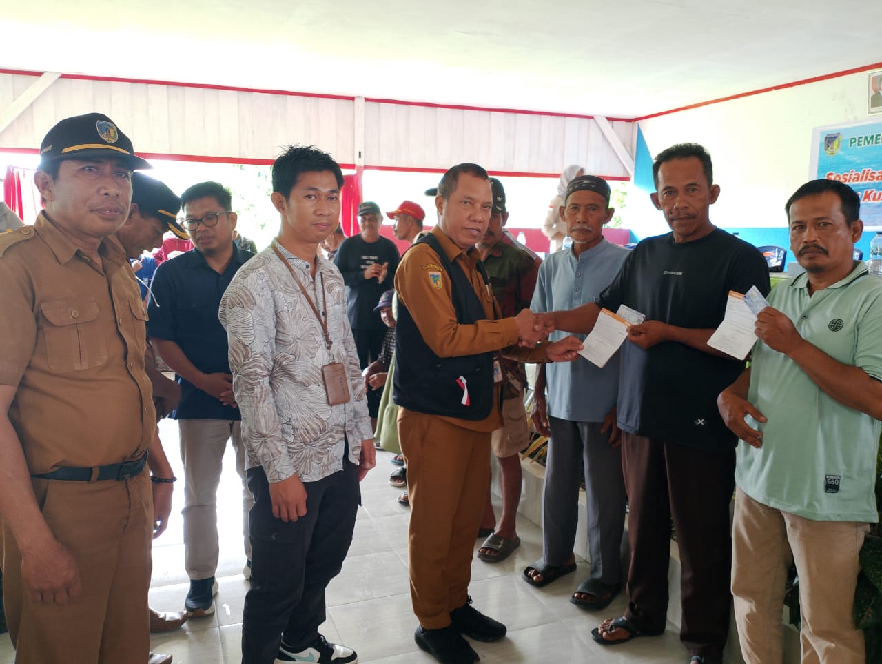 SERAHKAN : Kadis Perikanan Donggala Ali Assegaf, saat menyerahkan secara simbolis kartu Kusuka dan sertifikat tanah kepada nelayan di Sojol dan Sojol Utara, Selasa (16/09/2025).(FOTO: ISTIMEWA/RADAR P