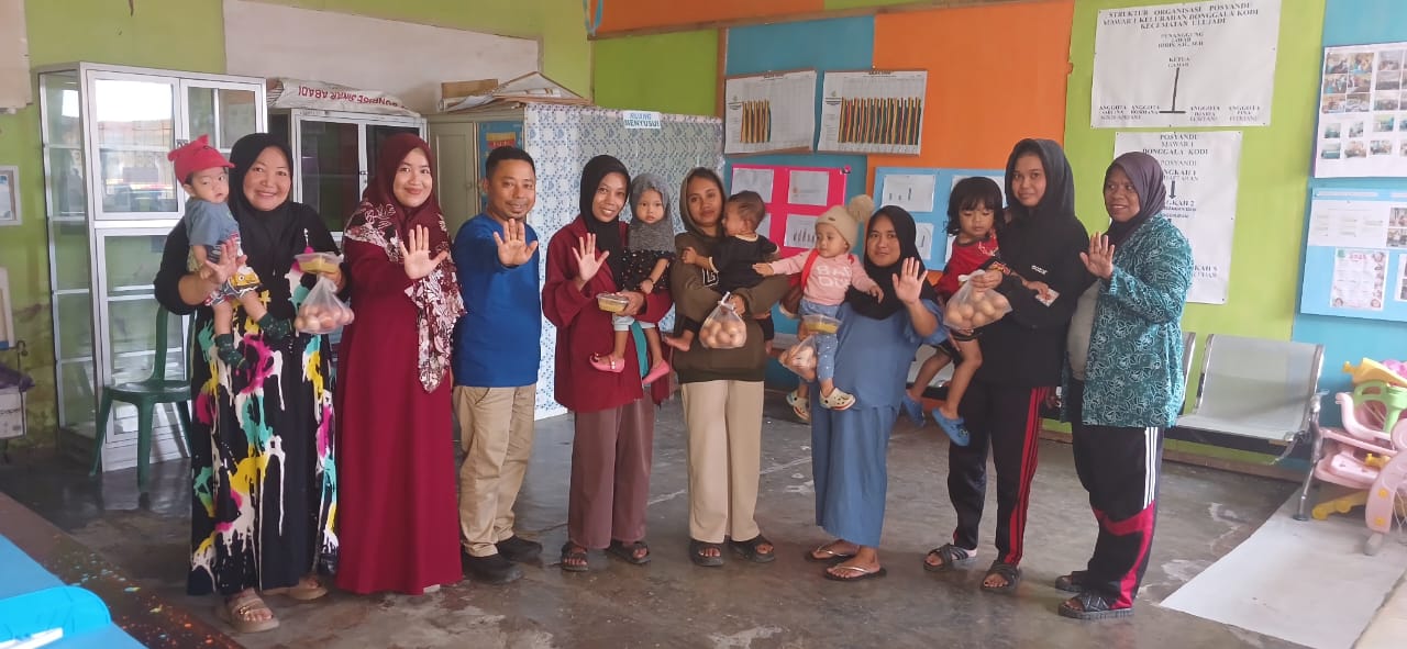 GEMBIRA: Lurah Donggala Kodi, Idris (tengah) berfoto bersama Ketua PKK Kelurahan bersama jajaran anggota PKK Donggala Kodi dan juga orang tua serta anak penerima bantuan gizi usai penyerahan makanan,