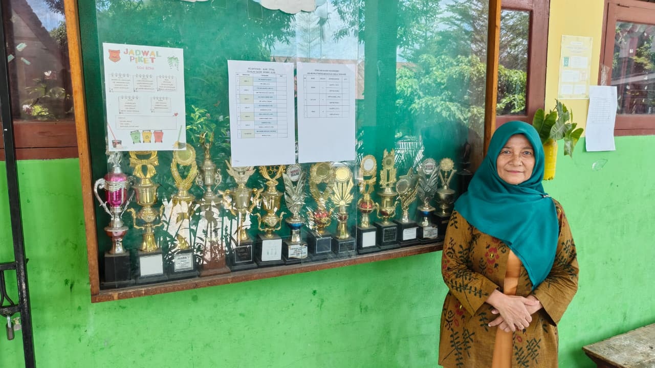 UKIR PRESTASI: Kepala SDN Biro Palu, Hartati Is Mentemas, berfoto di depan pajangan piala yang berhasil diraih oleh sekolahnya.  &lrm;