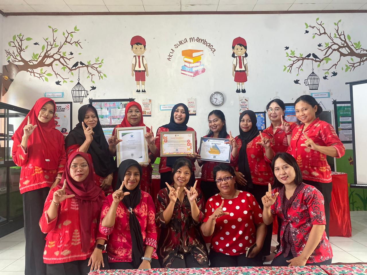 KOMPAK: Kepala SD Inpres 5 Lolu, Sukmawati (atas tengah)bersama dewan guru berada di tengah-tengah ruang perpustakaan sekolah dan memperlihatkan sertifikat penghargaan.