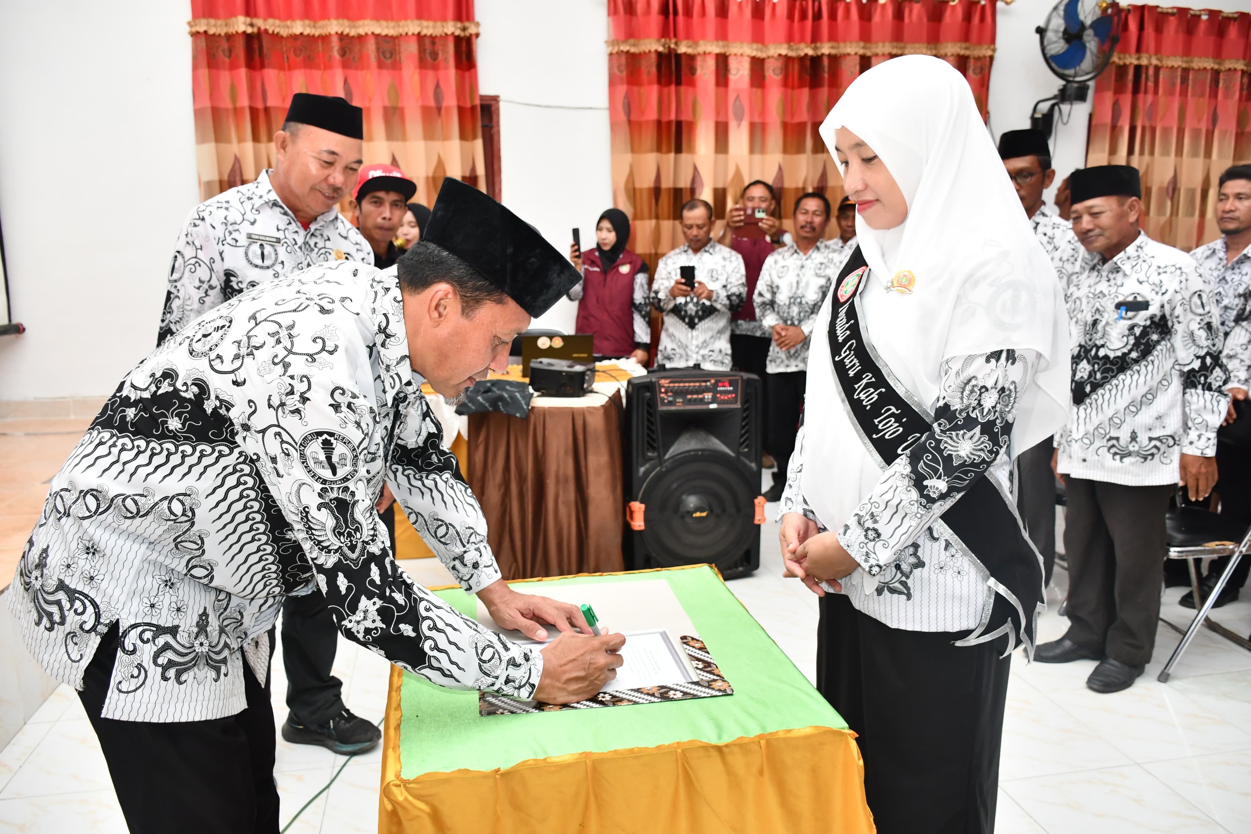 KUKUHKAN : Bupati Touna, Ilham Lawidu, mengukuhkan Ibu Hajar Lawidu, sebagai Ibunda Guru PGRI Kabupaten Touna 2025&ndash;2030.(FOTO: HERIYANTO LIMAHU).