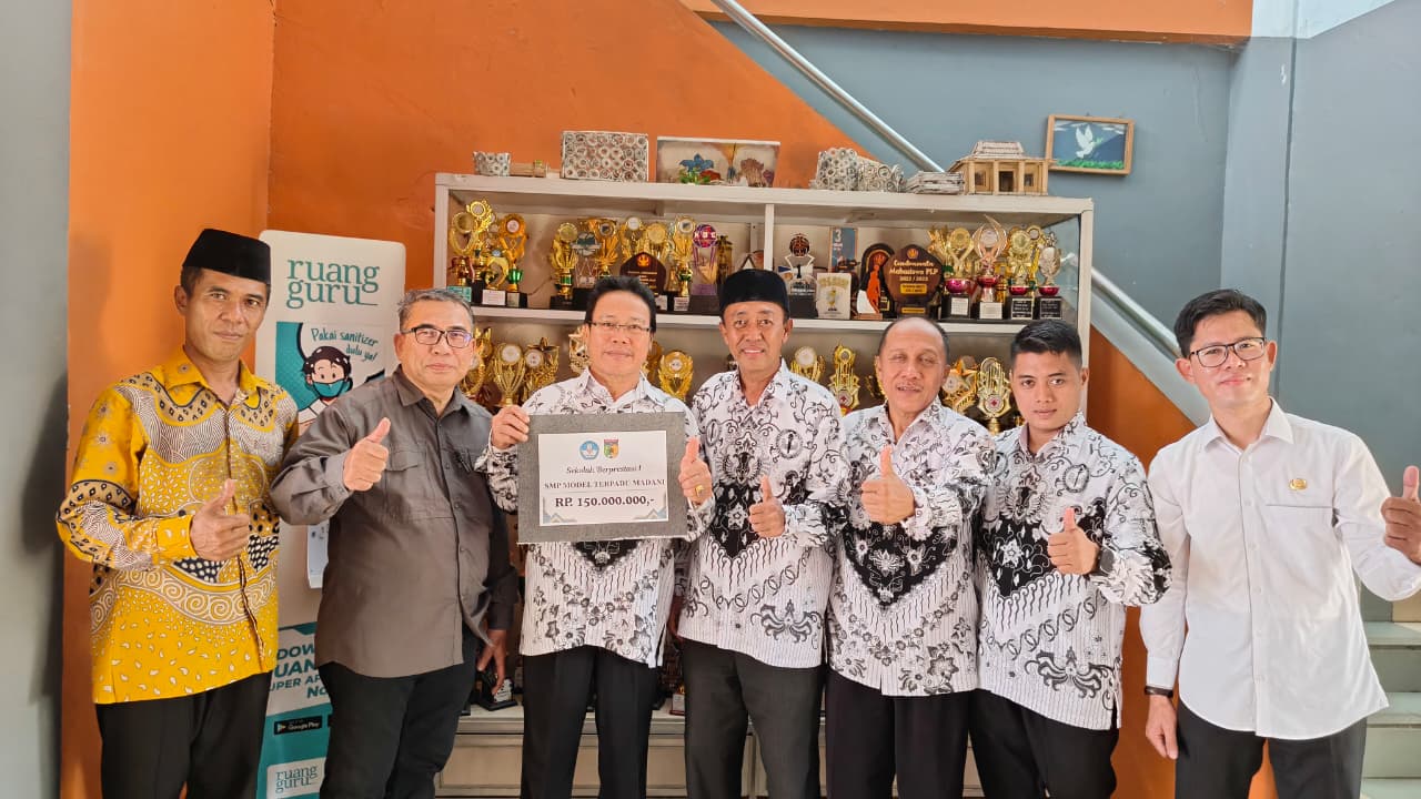 SEKOLAH BERPRESTASI: &lrm;Kepala SMP Model Terpadu Madani, Supriady M Djafar (tengah berpeci) bersama dengan jajaran dewan guru, memperlihatkan bukti sertifikat penghargaan dan deretan piala.