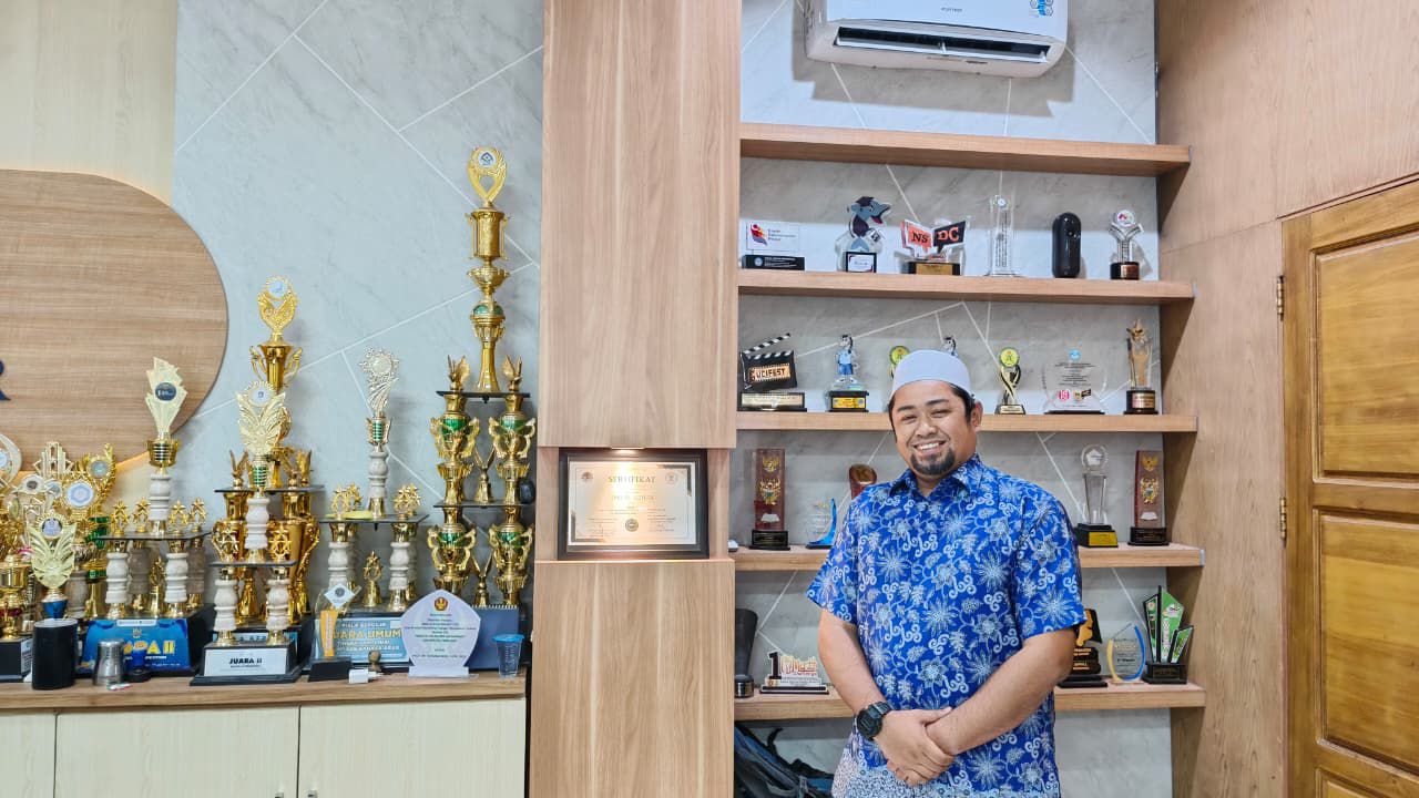 SEGUDANG PRESTASI: Kepala SMA Al-Azhar Mandiri Palu, Arafat Arsyad berfoto di etase piala yang menjadi bukti segudang prestasi yang diraih oleh pihaknya. Ini menjadi magnet bag calon siswa.