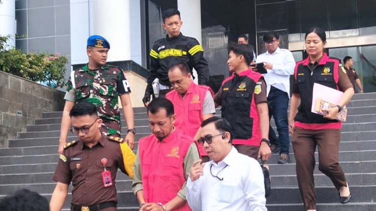 Dua tersangka kasus korupsi, Kadis PUPR Parimo dan PPK Morowali, digiring penyidik Kejati Sulteng menuju mobil tahanan usai menjalani pemeriksaan.