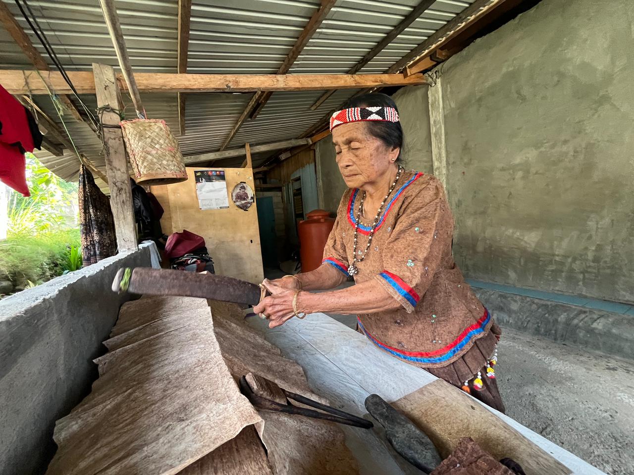 MENENUN: Ida Tobani, sedang fokus melakukan pekerjaan menenun kulit kayu yang sudah ditekuninya sejak lama.(FOTO: ANGEL SUMBARA/RADAR PALU).
