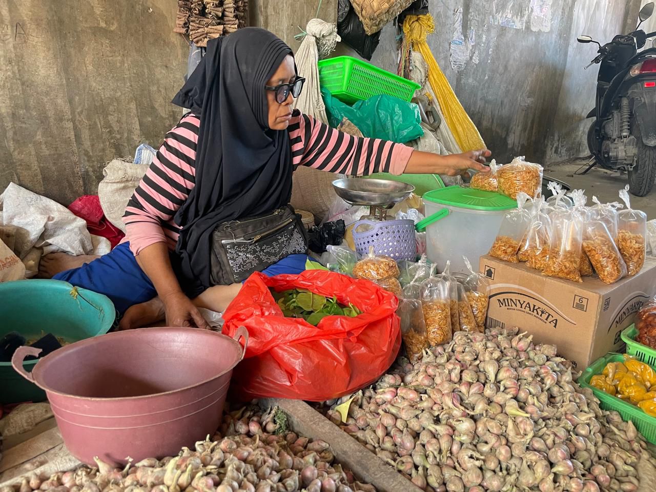 Pedagang bawang melayani pembeli di Pasar Inpres Manonda, Kota Palu, di tengah kenaikan harga akibat cuaca hujan.