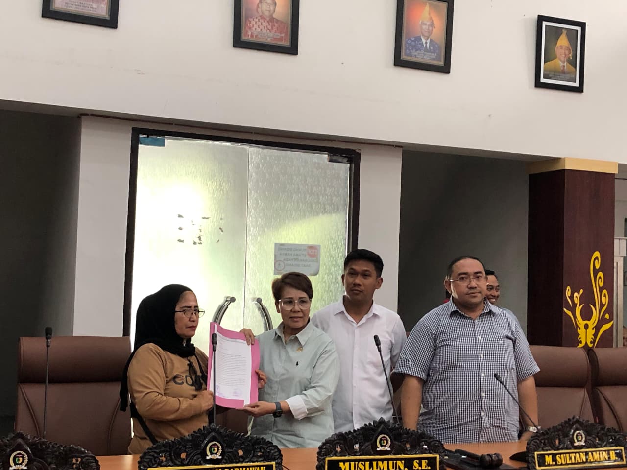 Perwakilan warga Poboya menyerahkan dokumen tuntutan kepada anggota DPRD Kota Palu saat audiensi di ruang rapat dewan, Rabu (18/2/2026).