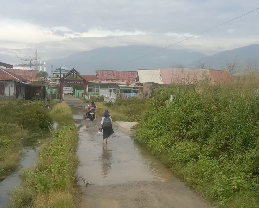 Siswa SMPN 10 Palu berjalan tanpa sepatu melewati genangan banjir rob di kawasan pesisir Pantai Talise, Kota Palu, saat air laut pasang merendam halaman sekolah.
