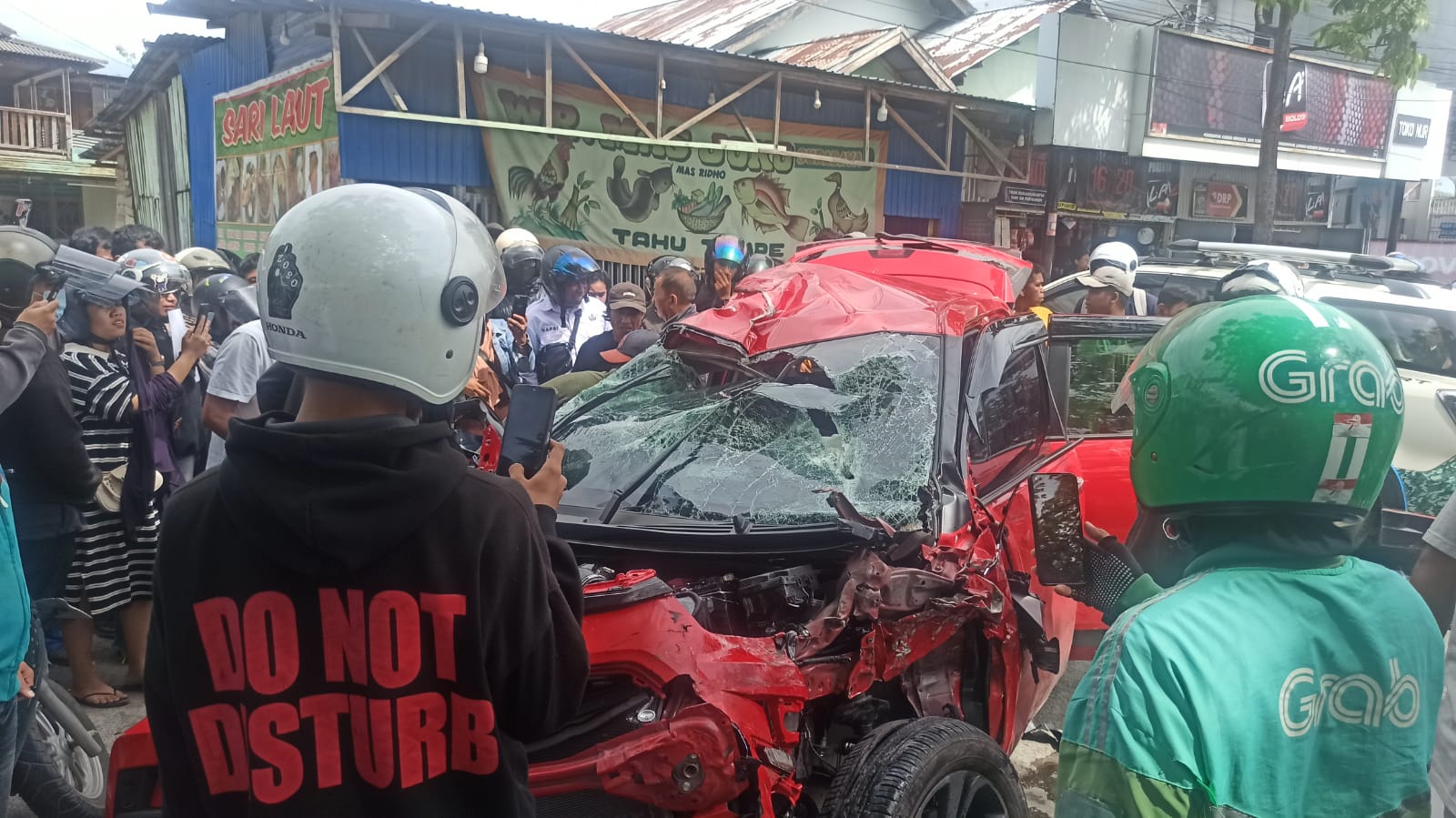 Warga berkerumun di lokasi kecelakaan beruntun di Jalan Yos Soedarso, Rabu (11/3), saat memberikan pertolongan kepada korban sebelum dievakuasi ke rumah sakit.
