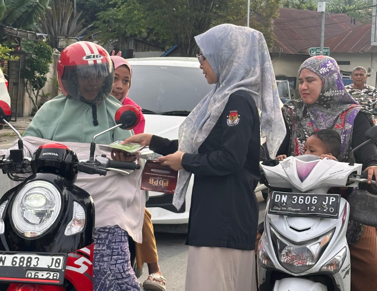 Petugas KPU Donggala membagikan selebaran sosialisasi cek data pemilih sekaligus takjil kepada masyarakat saat kegiatan pendidikan pemilih di bulan Ramadan.