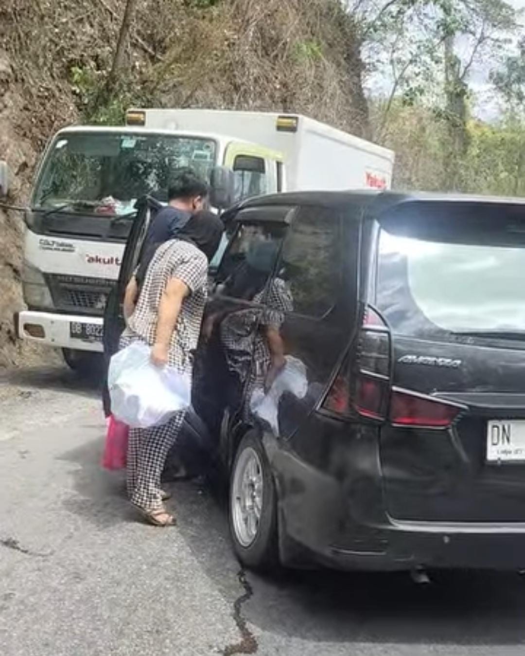 EVAKUASI DARURAT: Warga bersama pengendara yang melintas berupaya mengevakuasi korban kecelakaan antara mobil Toyota Avanza hitam dan truk distribusi Yakult di jalur Kebun Kopi Kilometer 6, Senin sian