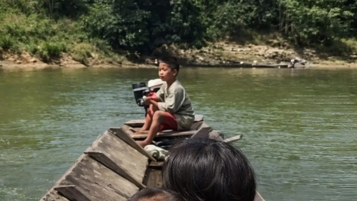Seorang bocah mengoperasikan perahu sambil menjaga adik-adiknya dalam video viral di media sosial. (tangkapan layar)