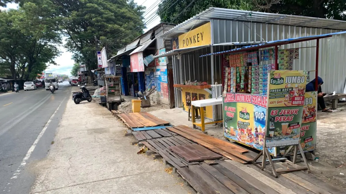 DITUTUP KAYU: Jejeran Pelaku UMKM yang berusaha di dekat drainase yang tidak ada plat penutupnya, usai drainase dikerjakan oleh kontraktor setahun yang lalu. FOTO: ANDIKA NUR HIKMAH
