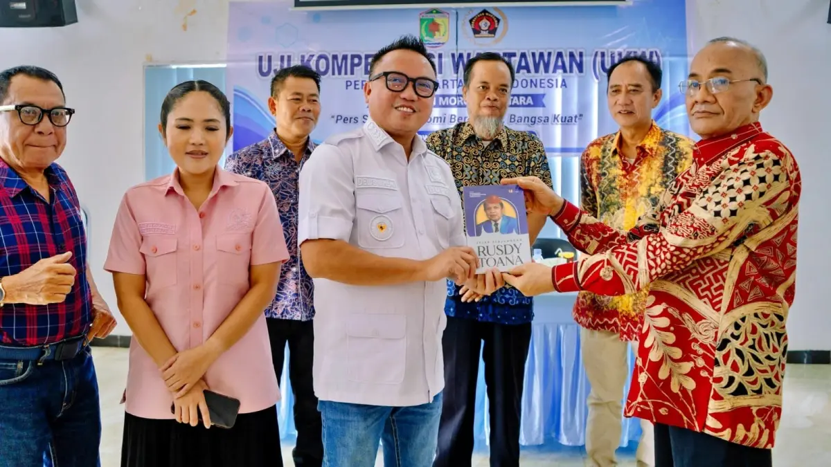 MENYERAHKAN BUKU: Ketua PWI Sulteng Tri Putra Toana menyerahkan buku Jejak Perjuangan Rusdi Toana kepada Bupati Morowali Utara Delis Julkarson Hehi pada pembukaan Uji Kompetensi Wartawanyang diselenggarakan PWI Morowali Utara, Jumat (8/5/2026). (FOTO: ISTIMEWA/RADAR PALU).