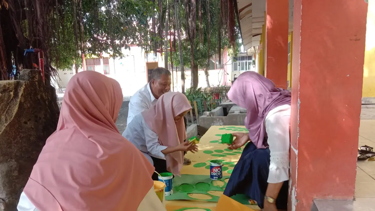Kebersamaan Wakasek dan para guru saat membuat mural daun kelor di ubin teras laboratorium IPA SMPN 18 Palu, rabu (13/5/2026). (Foto Ade Safitri/Radar Palu)