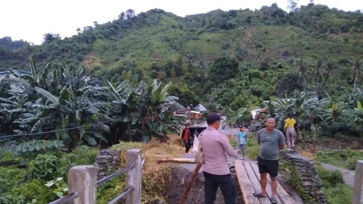 DARURAT : Personel Polsek Ampibabo bersama warga dan pemerintah desa membuat jembatan sementara menggunakan batang pohon kelapa setelah jembatan penghubung Dusun III dan Dusun IV Desa Sibalago, Kecamatan Toribulu, jebol diterjang banjir, Senin (25/5/2026).(FOTO: RAHMAT FADHIL/RADAR PALU)