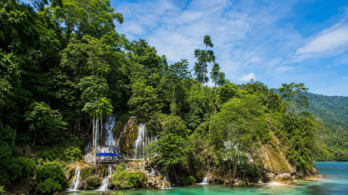 Pemandangan Air Terjun Bahomumpa di Bungku Selatan, Morowali, yang mengalir langsung ke laut dengan air jernih dan hutan hijau di sekitarnya. Foto: Instagram&nbsp;