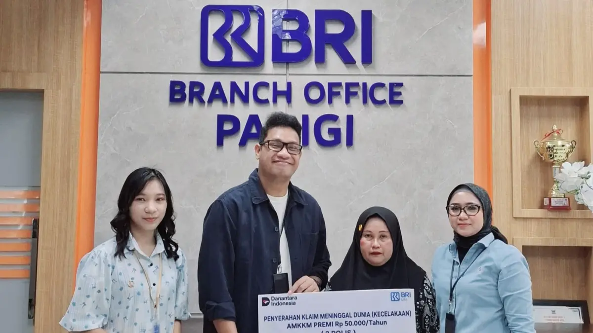 Branch Office Head BRI KC Parigi, I Dewa K. Yudyadana, menyerahkan secara simbolis klaim santunan meninggal dunia kepada ahli waris nasabah KUR BRI peserta Asuransi Mikro Kecelakaan Kesehatan Meninggal Dunia (AMKKM) BRILife di Kantor BRI KC Parigi.