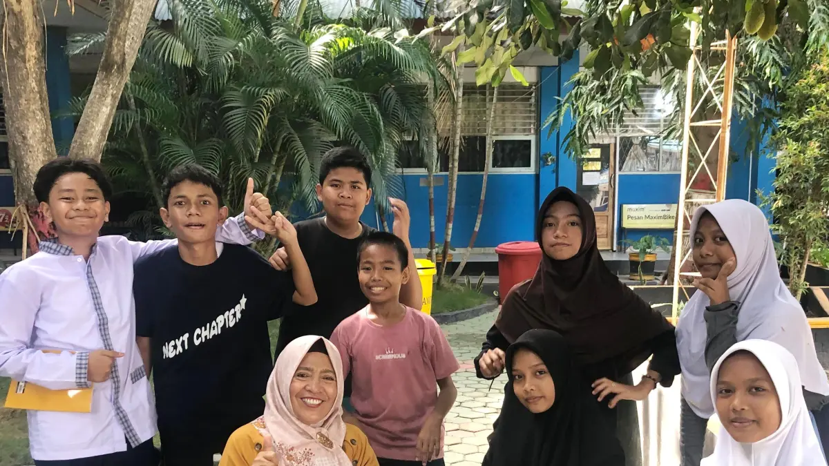BERSAMA MURID: Kepala SMPN 4 Palu,  Farida Batjo (tengah) bercengrama bersama murid di halaman kelas SMPN 4 Palu yang asri pada Jumat pagi (17/7/2026).(Foto: Nur Soima Ulfa/Radar Palu)