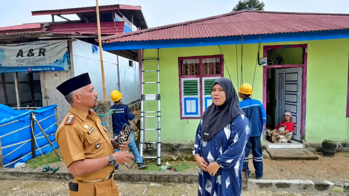 BERSYUKUR: Armila Tega di hadapan Pjs Kepala Desa Tanauge Faisal Dg Siame mengaku senang setelah petugas PLN melakukan instalasi listrik di rumahnya, Rabu (12/8/2026). (FOTO: ISTIMEWA/RADAR PALU)