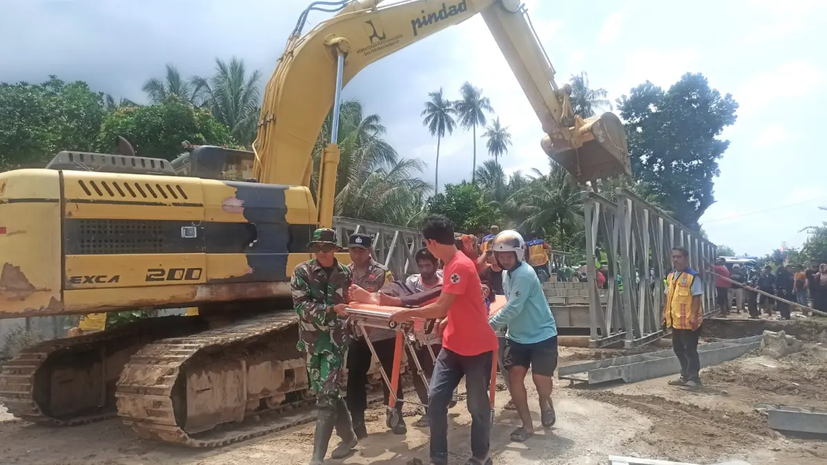 Pasien dari Puskesmas Tomini dievakuasi untuk dirujuk ke RS Anuntaloko Parigi Moutong, dengan melintasi jembatan sementara yang tengah dibangun untuk memulihkan akses akibat banjir, Sabtu (29/8). Foto : Wahono 