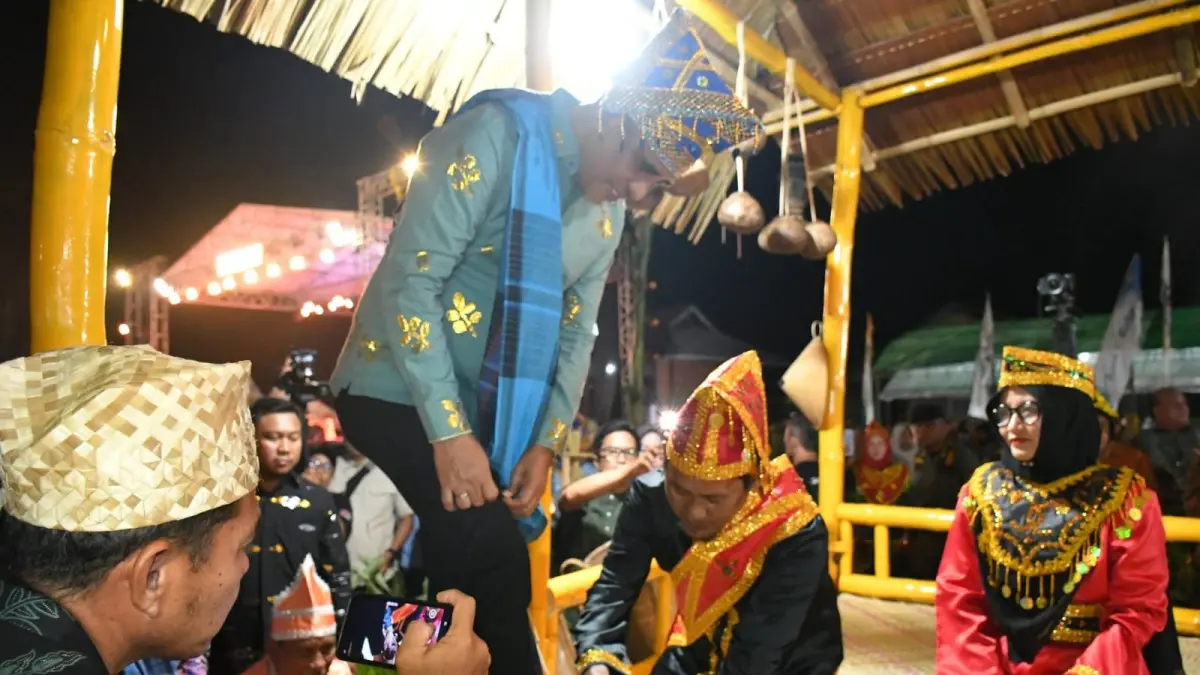 CUCI KAKI: Gubernur Sulteng, H. Anwar Hafid, menjalani prosesi mencuci kaki sebelum memasuki rumah adat.(FOTO: HERIYANTO LIMAHU/RADAR PALU).