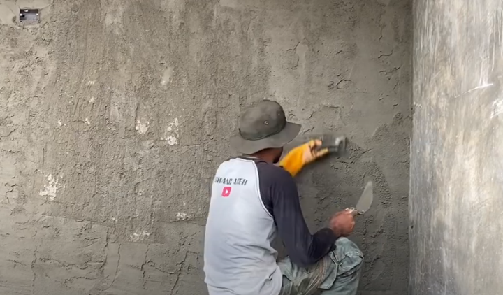 Tukang lagi asik mengerjakan plester aci di dinding rumah, bikin dinding mulus dan siap dicat.