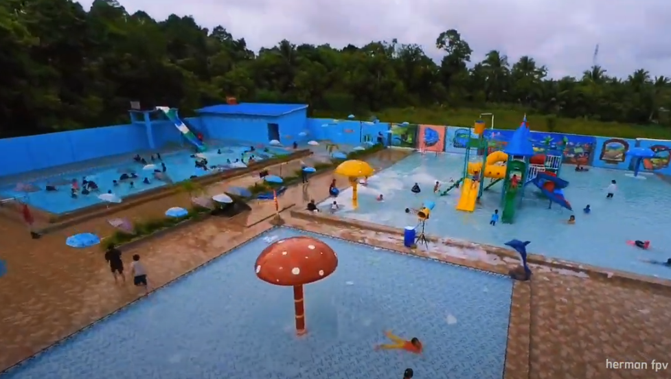 Selalu Ramaai dikunjungi diakhir pekan, Anak-anak riang bermain air di kolam renang Karang Joang Water Fun dengan latar belakang wahana permainan yang seru.