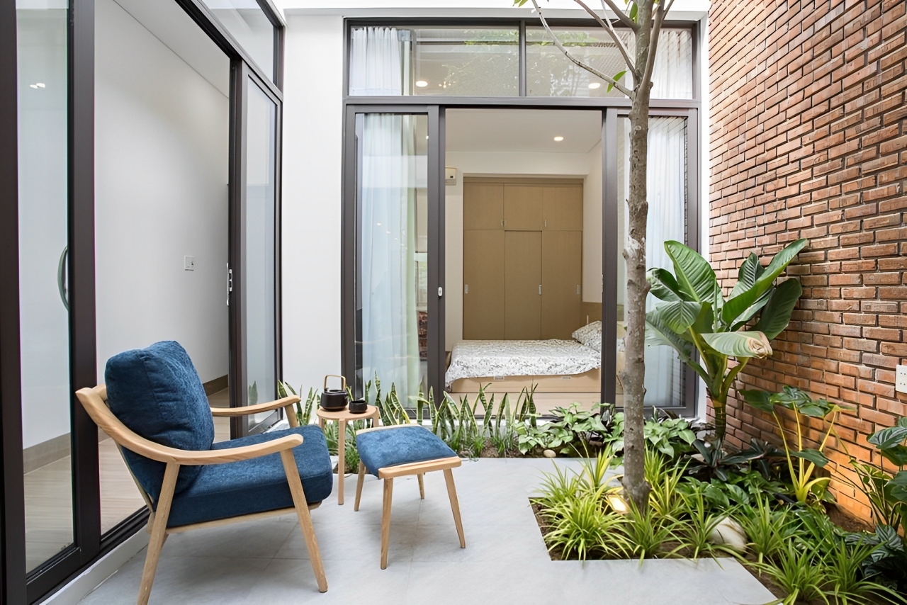 Interior rumah minimalis dengan elemen biofilik seperti cahaya alami, tanaman indoor, dan jendela besar. Desain rumah bernapas yang sehat dan kekinian.