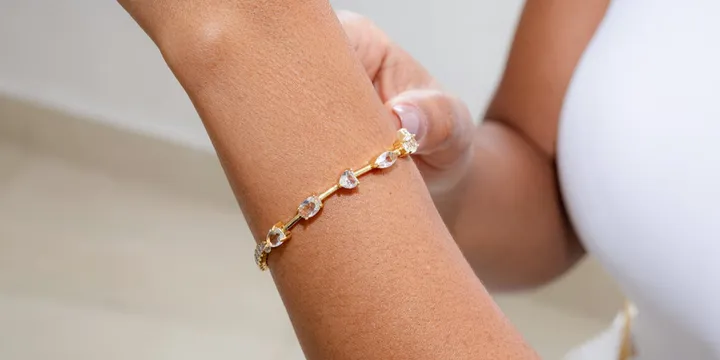 Gelang tali emas minimalis dengan liontin dan butiran emas kecil, pilihan aksesoris kece buat outfit kekinian. Cek tren viralnya disini Cess!