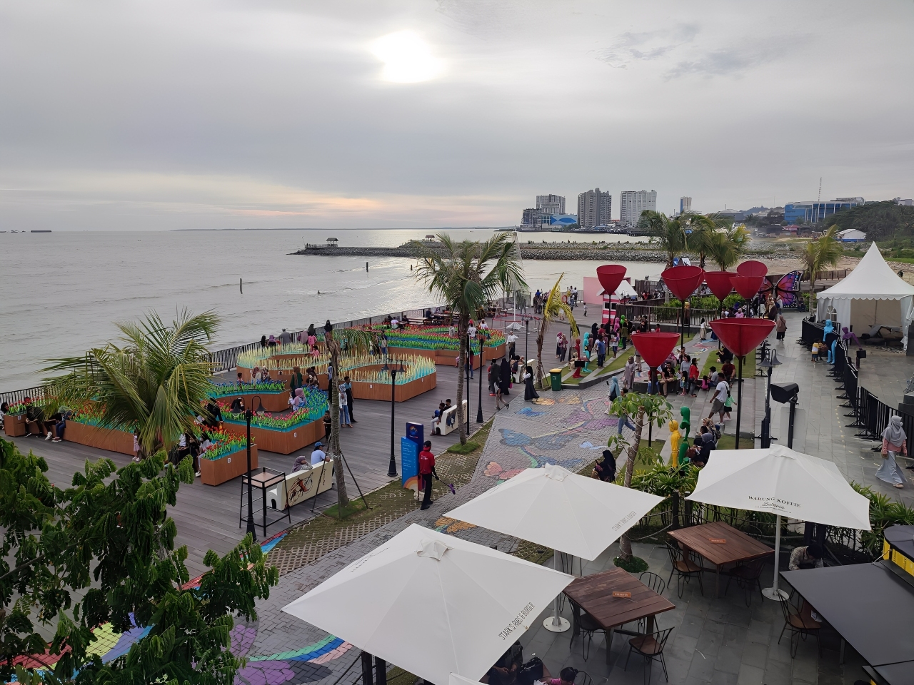 Pemandangan Pantai BSB Balikpapan saat sore hari dengan nuansa laut dan gedung modern, menggambarkan harmoni kota dan alam.