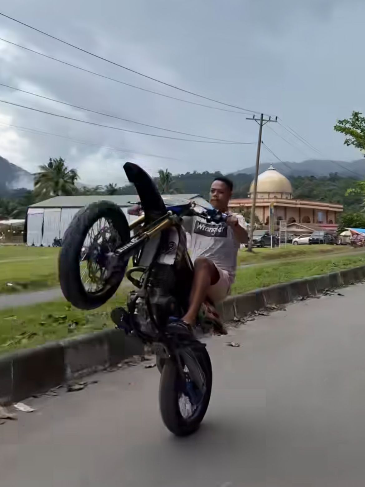 Pengendara motor mencoba aksi wheelie tapi hilang kendali, menabrak trotoar. Momen viral penuh pelajaran tentang keselamatan berkendara.